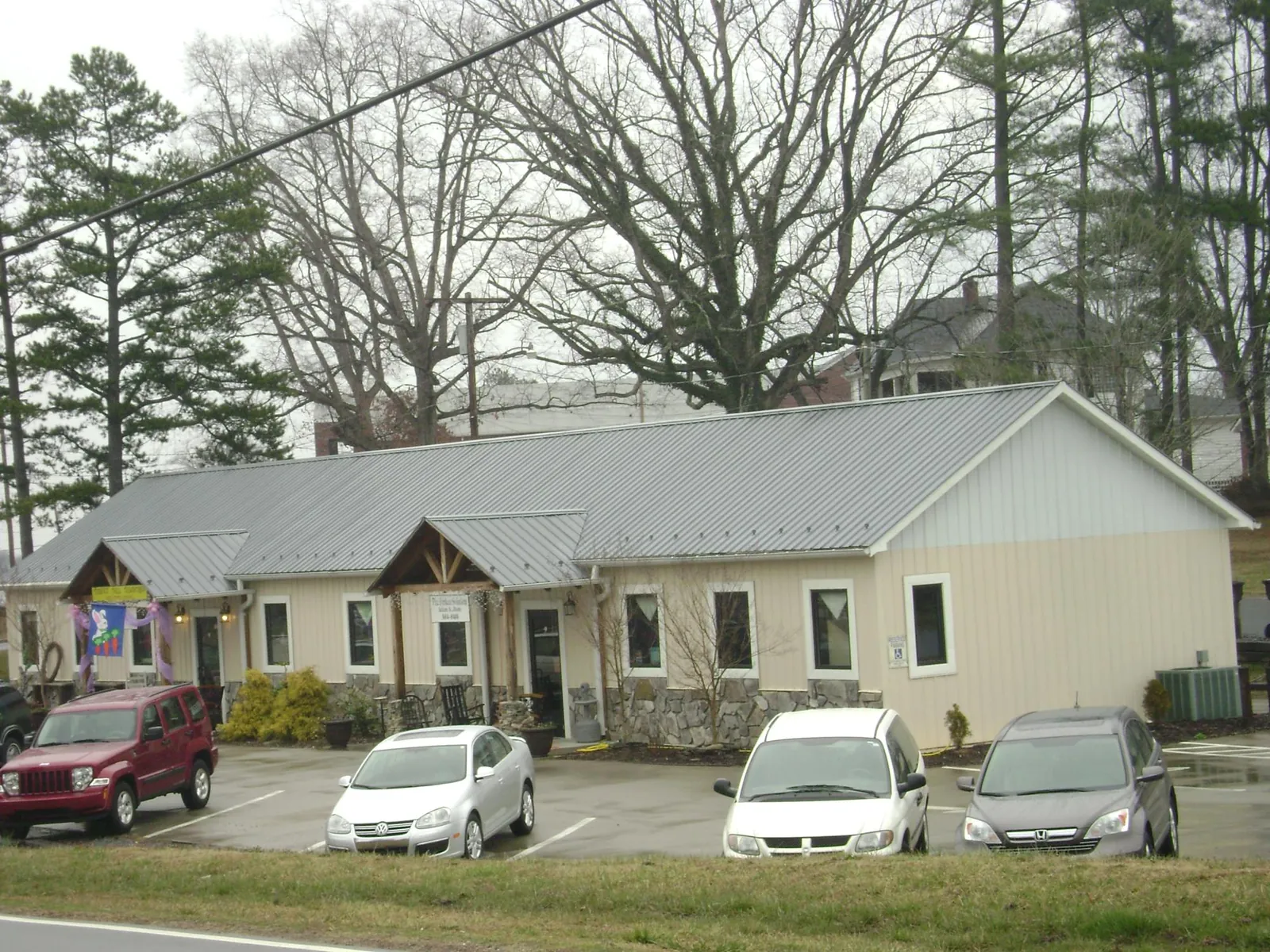 Gray metal roof with timber entry brackets on a small commercial building in Waveland